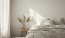 a large bed with pillows and a small table next to it with a plant on it